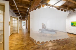 Chiropractor works on patient inside pod that can be raised or lowered in flexible work and gallery space