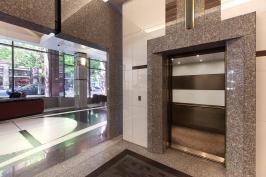 LEVELe-104 Elevator Interior with main panels in ViviChrome Chromis glass, White interlayer, Opalex finish; upper accent and handrail panels in Fused Nickel Silver, Sandstone finish; lower accent panel in Fused Nickel Silver, Sandstone finish, Dallas Impression pattern at 1000 Broadway, Portland, Oregon