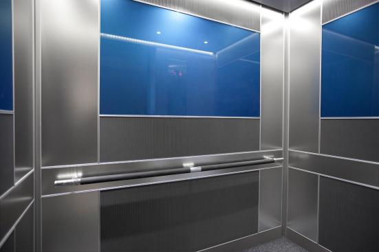 LEVELe-102 Elevator Interior with main panels in Bonded Aluminum with Dark Patina and Grass pattern; center accent panels in ViviChrome Chromis glass with custom color interlayer and Standard finish; side accent panels in Stainless Steel with Seastone Finish; Sextant handrail in Santoprene with Satin Stainless Steel Column finials at 101 Capitol Centre, Jackson, Mississippi
