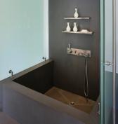Engineered stone forms the floor, tub, and wainscot of this master bath, which doubles as a pool cabana. Sliding glass partitions at the tub yield a variety of possible configurations.