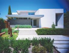A half-story above sidewalk level, this new suburban house stands at a dignified remove from the public realm, but opens wide to its private side and new gardens.