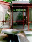 A glass-roofed connector ties the porch to the house and lets daylight into the adjacent dining room. Rainwater flows from the slanted roof into a scupper poised over a collector bowl set in a water trough.