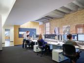 The main entrance to the office is on the third floor. The reception desk is just visible at the back of the space. Behind the wall with the bulletin board is a kitchen area.
