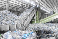 An escalator with a pile of plastic bottles at a factory for processing and recycling PET plastic.