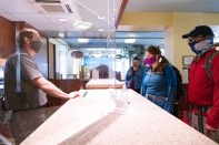 A ranger greats visitors through a plexiglass window at the Yellowstone National Park visitor center desk