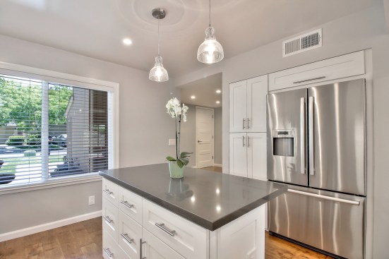 White shaker cabinet, Open space kitchen with quartz counter top. 
Wood flooring 
