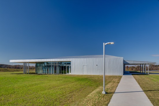 From the parking area, both the renewable-energy exhibit and the covered entry are apparent. A Fire Marshal-directed exit door was detailed into the standing-seam metal wall. 
