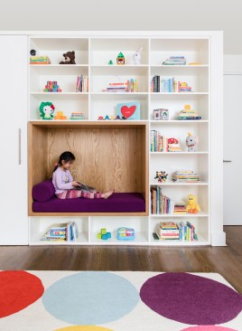 Child's bedroom with white oak reading nook accenting the floor to ceiling bookshelves