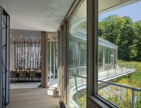 The dining area opens onto a pond-side deck with a custom railing made of stainless steel and cable by Malove Laser.