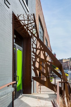 Front exterior entrance to building showing corten steel railing and screen shading device