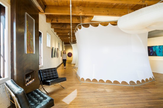 Guest seating and fireplace in chiropractor's office with white pods that can be raised and lowered for a flexible office and event space