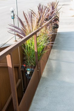 Unique artistic corten steel railing and planter next to handicapped ramp