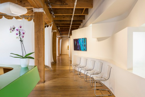 View from front desk of chiropractor's office with white pods that serve as treatment rooms