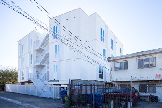 The structure is clad in a combination of high-density fiber cement board from James Hardie and perforated, fluted metal panels from Metal Sales, both of which are painted white. 