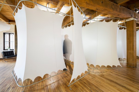 Stretched white spandex pods on metal frames create a flexible work space in a chiropractor's office - man walking into a pod