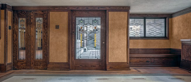 The restored front door and foyer, with repainted plaster, refinished magnesite floors, and restored wood trim. 
