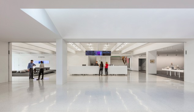 The renovated lobby in the Barnes building features a new seating area, ticket counter, and gift shop, in a space that now has floor-to-ceiling windows. Stairs behind the ticketing desk lead the the galleries in the Barnes building.