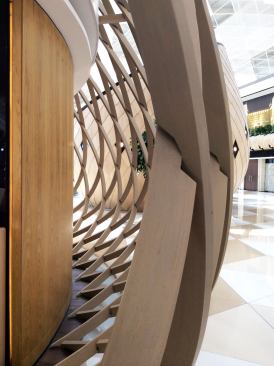 Building systems—HVAC ducts, speakers, smoke detectors, and electrical channels—are tucked into the cavity between the cocoon’s lattice structure and cladding, while lighting elements are embedded flush in the wooden surface. In open-lattice cocoons, the systems are hidden underneath flooring finishes.