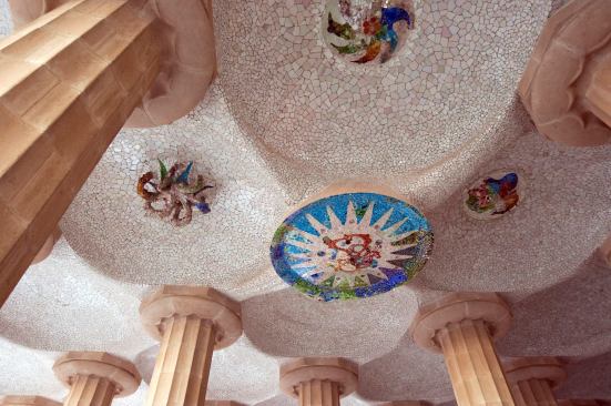 The Hypostyle Room features mosaic tile centerpieces by Gaudi that symbolize the seasons. The work exemplifies Gaudi's mastery of trencadis, or broken pieces of ceramic reassembled to create a mosaic.