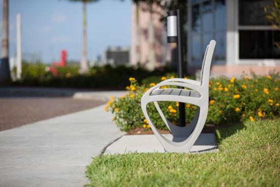 Trio Bench shown in 6 foot, backed configuration with Aluminum Texture powdercoated frame and clear anodized aluminum slats; Buttler Ash Receptacle shown in medium, pole-mount configuration with Black Texture powdercoated endcaps and Silver Anodized powdercoated cylinder at Page Field, Fort Meyers, Florida