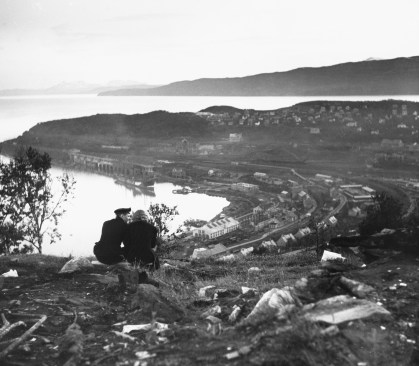 A German sailor and Norwegian woman sitting above war-damaged Narvik, Norway, 1941