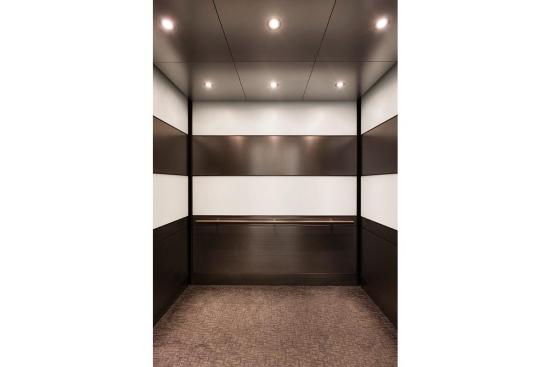 LEVELe-104 Elevator Interior with main panels in ViviChrome Chromis glass, White interlayer, Opalex finish; upper accent and handrail panels in Fused Nickel Silver, Sandstone finish; lower accent panels in Fused Nickel Silver, Sandstone finish, Dallas Impression pattern; Round Handrail at 1000 Broadway, Portland, Oregon