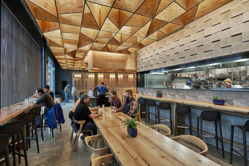 Glowing plywood ceiling illuminated by Type A–lamp pendants above dining area