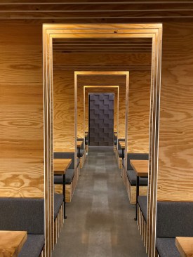 Type A lamps concealed in the millwork frame the entry to the booth area.