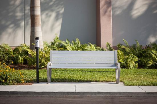 Trio Bench shown in 6 foot, backed configuration with Aluminum Texture powdercoated frame and clear anodized aluminum slats; Buttler Ash Receptacle shown in medium, pole-mount configuration with Black Texture powdercoated endcaps and Silver Anodized powdercoated cylinder at Page Field, Fort Meyers, Florida