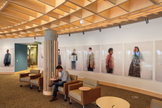 The forum’s wood ceiling extends over the balcony area and houses downlights and wallwashers for the art display wall.