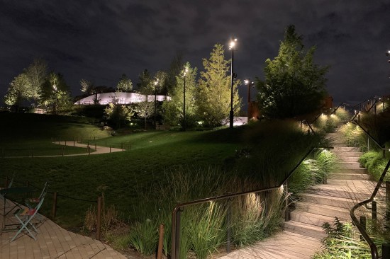 Lights—concealed within rails, behind concrete boulders, ground cover, and in the case of the few light poles, nestled between trees—create an integrated environment where luminaires are seldom noticed.