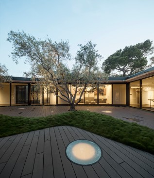 Skylights and a subtle lighting of landscape elements against a glowing interior promote seamless indoor-outdoor living.