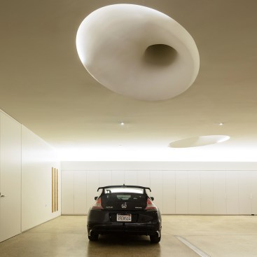 When daylighting is not available, indirect light sources illuminate the sinuous coves in the garage, supported by a crisp layer of down lights.