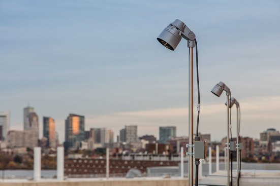 The fixtures that illuminate the site are pole-mounted on the surrounding buildings.