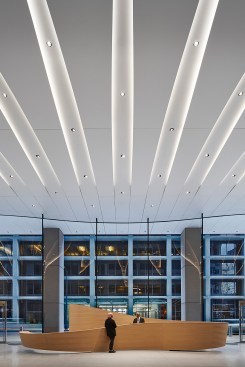 The ceramic ceiling unfolds towards the welcome desk and curved glass façade outside with the adjacent tower beyond.