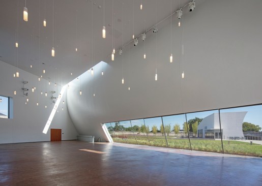 The Skylight Pavilion has an end-grain cherry wood floor under a series of suspended lights that allow it to serve either as a performance venue or as an events space. While the daylight and views are a selling point, custom shades can be deployed to cover all of the glazed surfaces (including the skylight and curved windows) if a performance requires it.