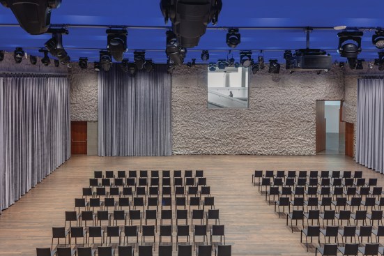 Studio K is the largest performance space in The Reach. Its dimensions mimic those of the stage of the Opera House in Stone’s building, so that the company can rehearse at full scale. The walls are lined with crinkle concrete, and the room is topped with a sawtoothed bubble slab, in a vivid blue. An interior window admits daylight from the Welcome Pavilion, to maintain a connection with the outdoors.