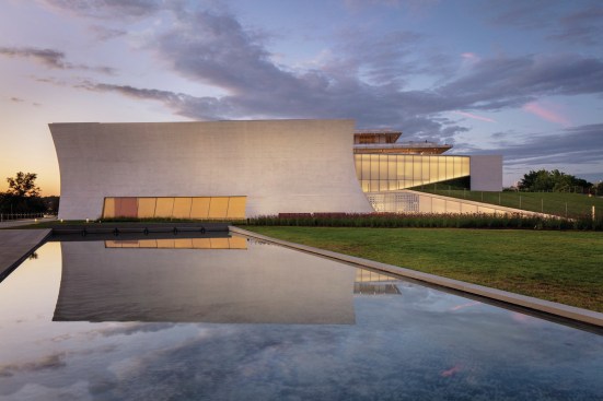 Skylight and Welcome Pavilions at dusk. From the south, the glass cuts that reveal the spaces underneath The Reach’s green roof become evident. Visitors can access the garden of tall grasses and wildflowers by walking over and down the lawn, developed with Hollander Design Landscape Architects, or by following a path from the Stone building down the west side of the site (at left). From the path, pedestrians can look into lower-level performance and pedestrians rooms.