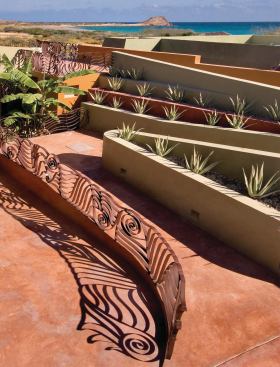Large doors open to curving terraces covered in palapa, or palm fronds, tied down with fish netting. Flanked by spiky agave and sculptural railings, the ramp becomes a stroll in the garden.

