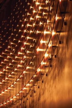 Steel brackets attach the mirrors and 1,280 LEDs to tensioned steel wires that run vertically inside the silo wall.