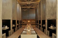The dining room’s centerpiece— a large communal dining table— juxtaposes
 the space’s verticality, while large monolithic concrete booths provide
 a more intimate dining setting.